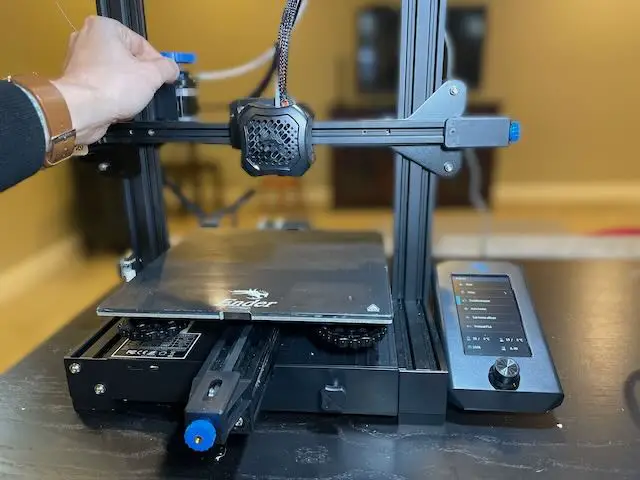 Removing the blue clip from an Ender 3 v2 to release the Bowen tube