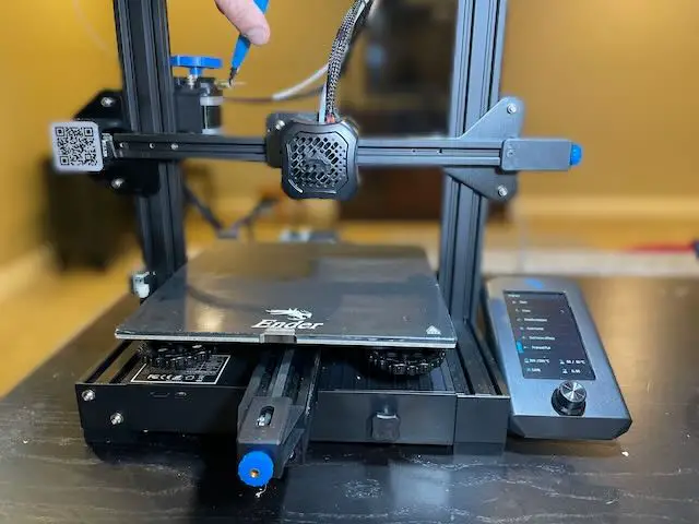 Cutting 10mm of filament that was sticking out of an Ender 3 V2 extruder where the Bowden tube used to be.