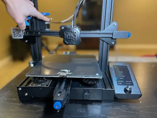 A finger pointing to where no more filament is sticking out of an Ender 3 V2 extruder.