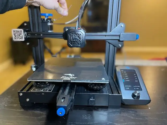 Fingers holding approx 100mm of extruded filament hanging out of an Ender 3 V2 extruder.