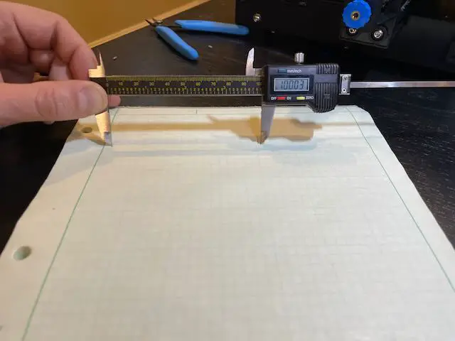 Calipers measuring marks on a paper showing 100mm